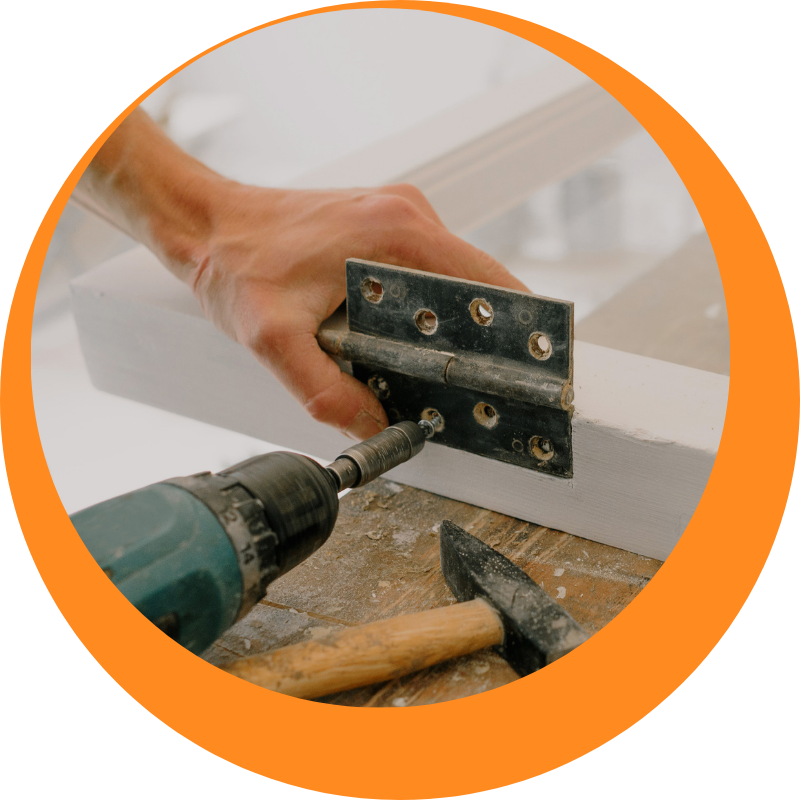 A handyman in Camperdown installing a metal hinge on a wooden frame with a power drill, showcasing professional home improvement and repair skills.